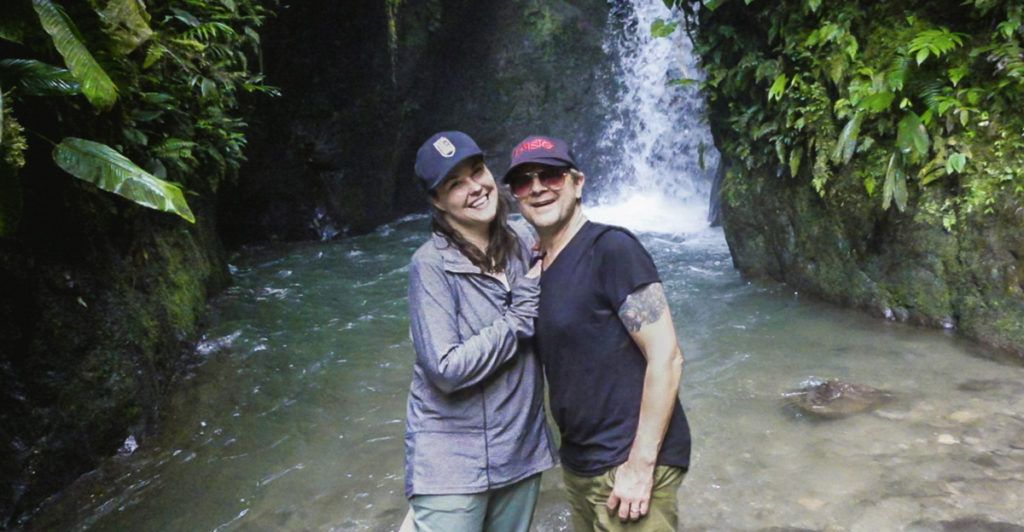 man and woman standing in pool of water at one of the waterfalls in the Mindo Nambillo Ecological Reserve. Mindo, Ecuador